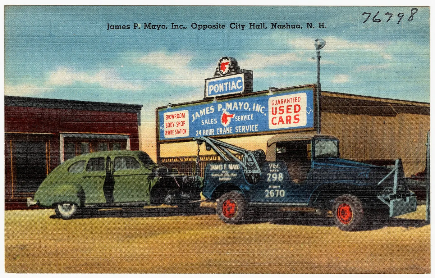 An old postcard of a garage with a tow truck out front